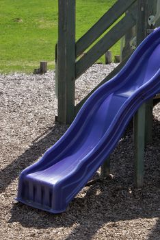 A small childrens slide is part of a recreational toyhouse located in a public park.