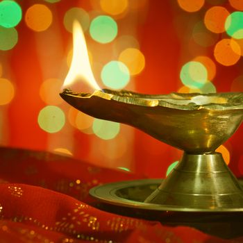 A metallic traditional Indian lamp illuminated in dark. Diwali Greetings.