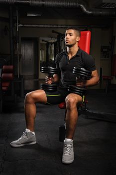 handsome young african descent mixed race man sitting and resting on bench in gym