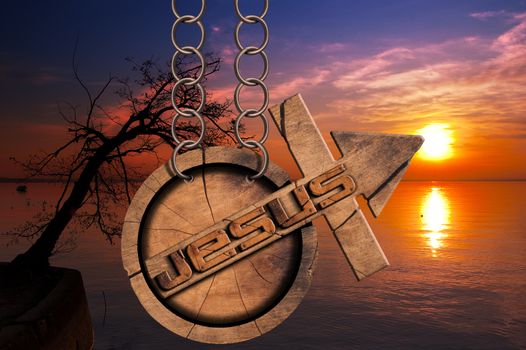 Wooden symbol with cross and arrow upward and text Jesus. Hanging from a chain at a beautiful sunset over the lake with clouds