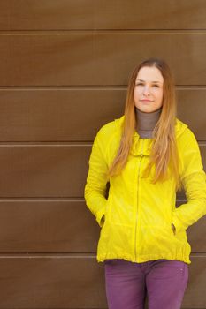 Beautiful fashionable girl in a jacket  in autumn on a background of a wall