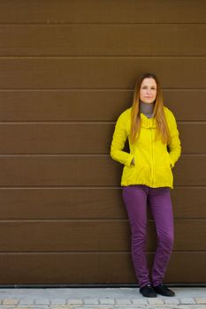 Beautiful fashionable girl in a jacket  in autumn on a background of a wall