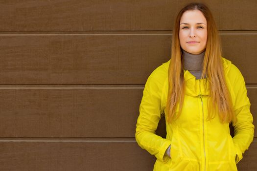 Beautiful fashionable girl in a jacket  in autumn on a background of a wall