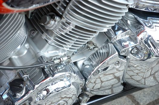 Closeup photo of motorbike engine with shiny chrome parts, different metal components.