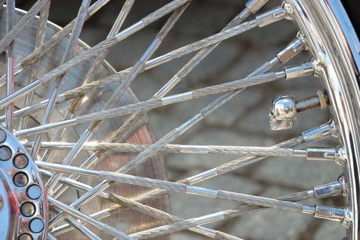 Closeup photo of motorcycle wheel with shiny spokes and metallic rim.