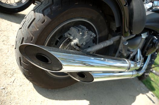 Photo of motorcycle from behind with big tire and two metallic exhaust pipes.