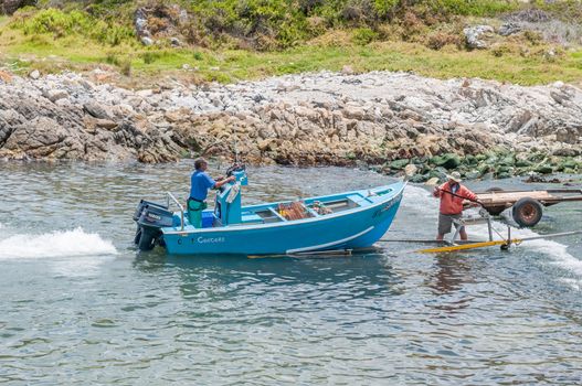 KLEINMOND, SOUTH AFRICA - DECEMBER 23, 2014: Crayfish boat being pulled with the days catch onto a trailer at Kleinmond harbor