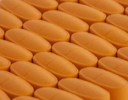 bunch of orange vitamin pills spilled on the table