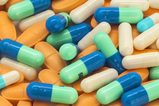 pile of blue-green and orange pills spilling on the table