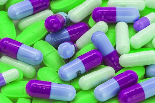 pile of green and blue-violet pills spilling on the table