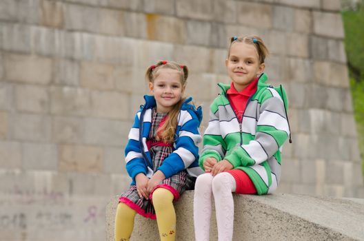 two girls of four and six years of walking on the embankment of the river