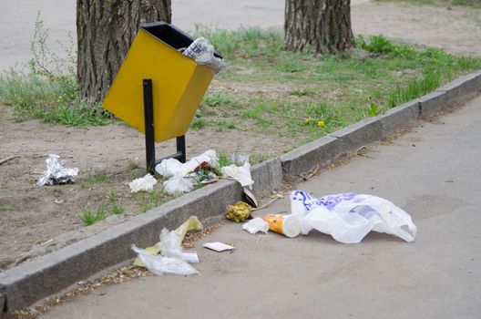 Debris is scattered around the garbage bins on a city street