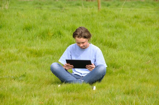 Girl sitting on the lawn and using digital tablet