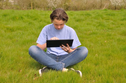 Girl sitting on the lawn and using digital tablet