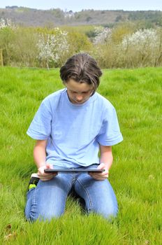 Girl sitting on the lawn and using digital tablet