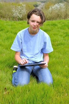 Girl sitting on the lawn and using digital tablet