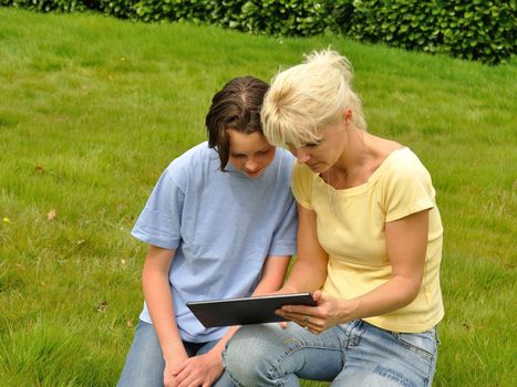 Family sitting on the lawn and using digital tablet