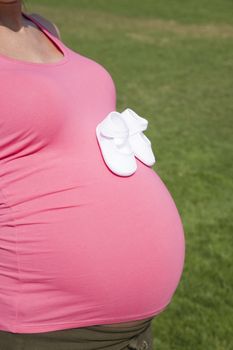 pink pregnant woman with baby bootees in hand