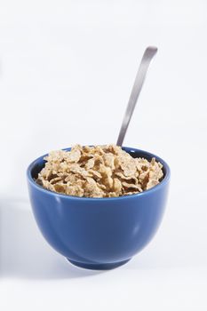 still life blue big bowl with cereals corn and silver spoon on white