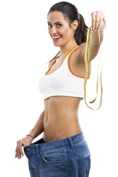Woman with large jeans in dieting concept holding a measuring tape