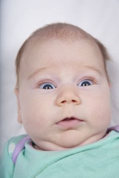 one month age newborn baby face open eyes looking at camera with terror fright face