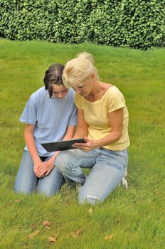 Family sitting on the lawn and using digital tablet