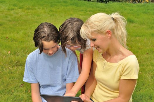 Family sitting on the lawn and using digital tablet