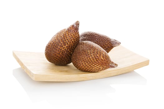 Salak fruit on wooden plate isolated on white background. Tropical fruit, asian cooking and eating. 