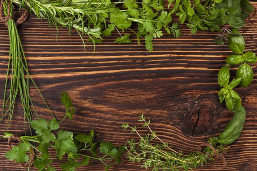 Culinary herbs background with copy space. Fresh basil, cilantro, chive, parsley and mint herbs on brown wooden background with copy space.