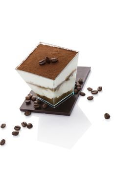 Tiramisu dessert on chocolate bar with coffee beans isolated on white background. Italian sweet dessert concept.