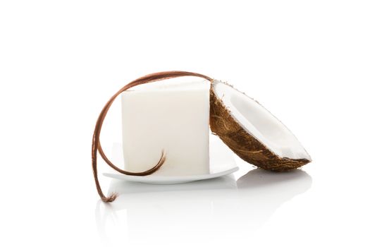 Organic hard coconut oil with a string of hair and half coconut isolated on white background. Natural organic cosmetics, body and hair care.