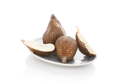 Salak fruit on plate isolated on white background. Tropical fruit, asian cooking and eating. 