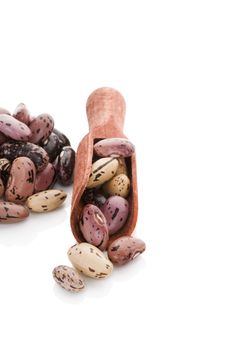 Pinto beans on wooden scoop isolated on white background. Healthy legume eating.