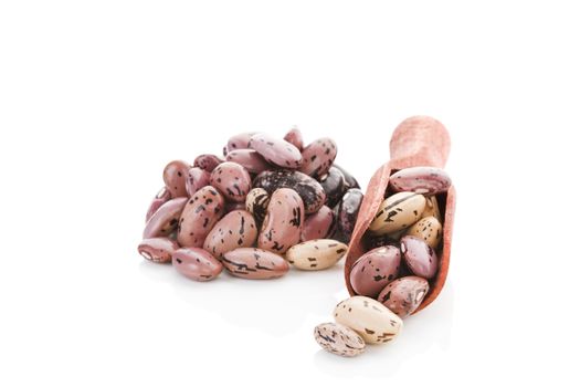 Pinto beans on wooden scoop isolated on white background. Healthy legume eating.