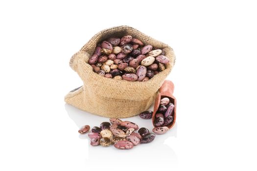 Pinto beans in burlap bag with wooden scoop isolated on white background. Healthy legume eating.