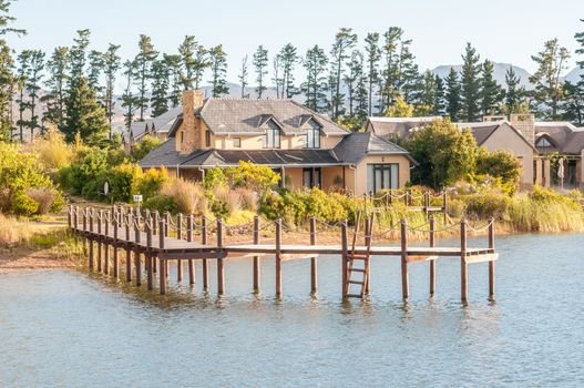 CAPE TOWN, SOUTH AFRICA - DECEMBER 18, 2014: Early morning view of houses next to a dam with jetty on the Wedderville Estate near Sir Lowrys Pass