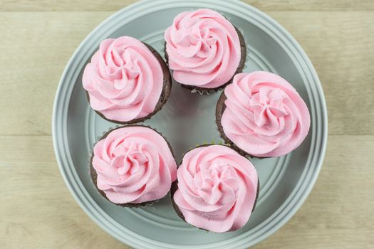 Chocolate flavored cupcakes frosted with pink buttercream frosting.