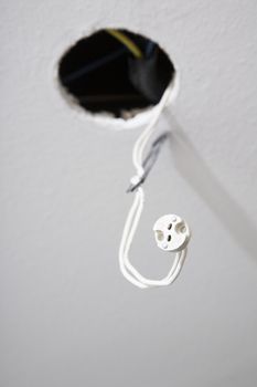 white indoor ceiling with circular hole cable with plug ready for spotlight recessed