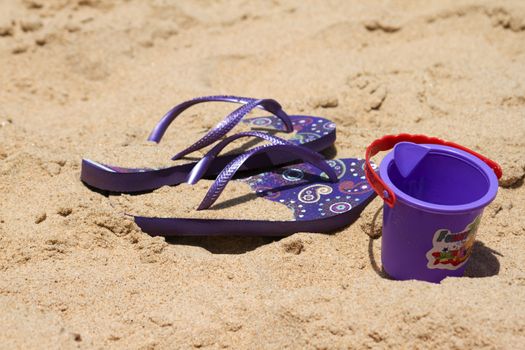 Children's sandy toys and flip-flop on a beautiful beach. India Goa.