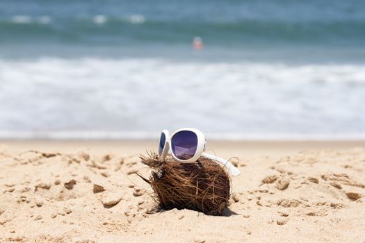 Coconut  and a sunglasses on a beautiful beach. India Goa.