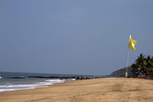 Beautiful sandy beach with a yellow flag. India Goa.