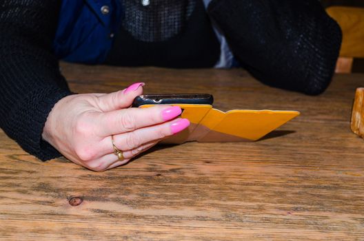 A woman sitting at the table and holding a phone in his hand.