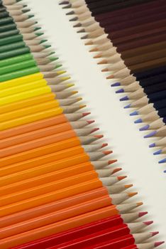 Abstract composition of a set wooden colour pencils against a white background