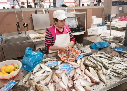 LOULE, PORTUGAL - APRIL 4: Woman cleaning the fish for selling in the traditional portuguese market in Loulele on  April 4th 2015 in Loule, Algarve, Portugal, this market is the biggest market hall of the algarve