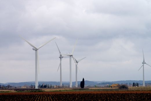 White Electrical Power Generating Wind Turbines on Spring Cloudy Skies background, France