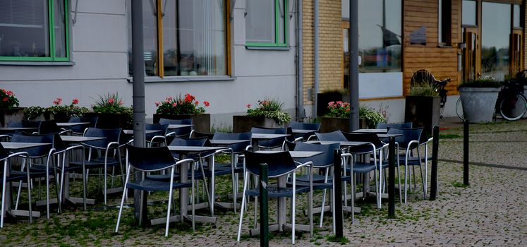 Contemporary Street Cafe with Steel Tables and Black Chairs on Paving Stone in Malmo, Sweden