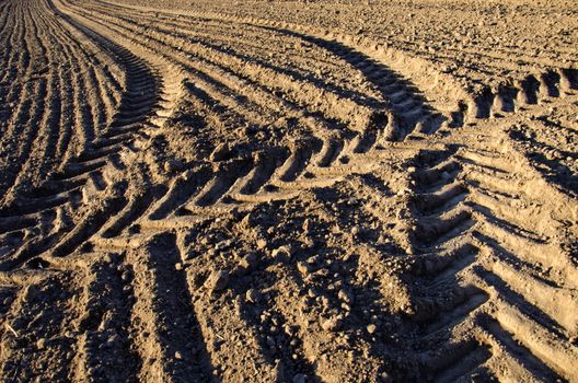 agriculture tractor traces on cultivated farm field soil