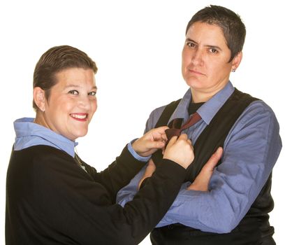 Smiling woman adjusting necktie of serious girlfriend