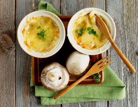 Delicious Champignon Mushroom Julienne in Ramekins with Wooden Forks and Napkin on Rustic Wooden background. Top View