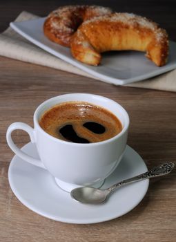 cup of coffee on the table with freshly baked buns 